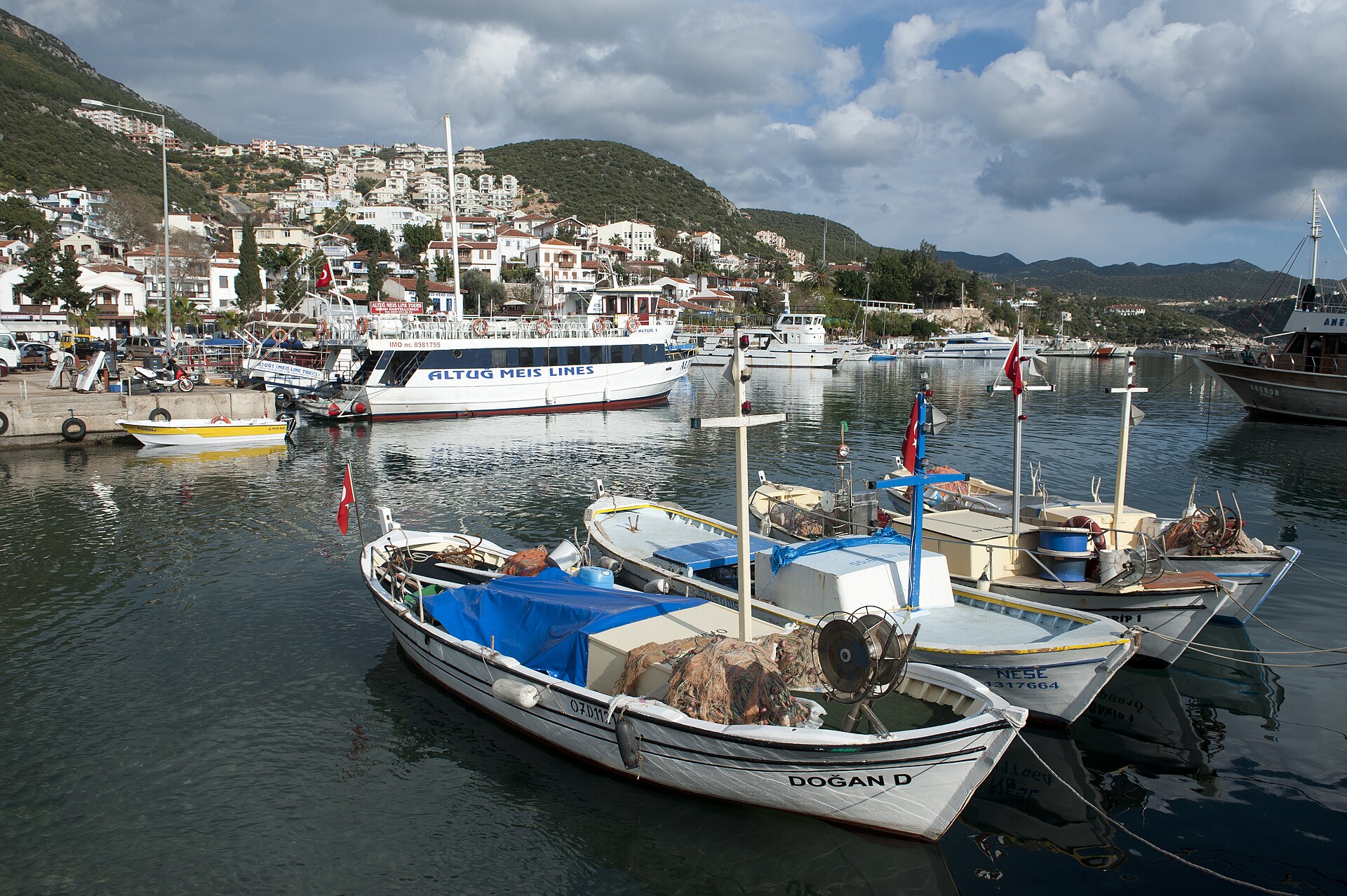 Fishing boats moored in Kaş harbour with whitewashed houses climbing the hill behind